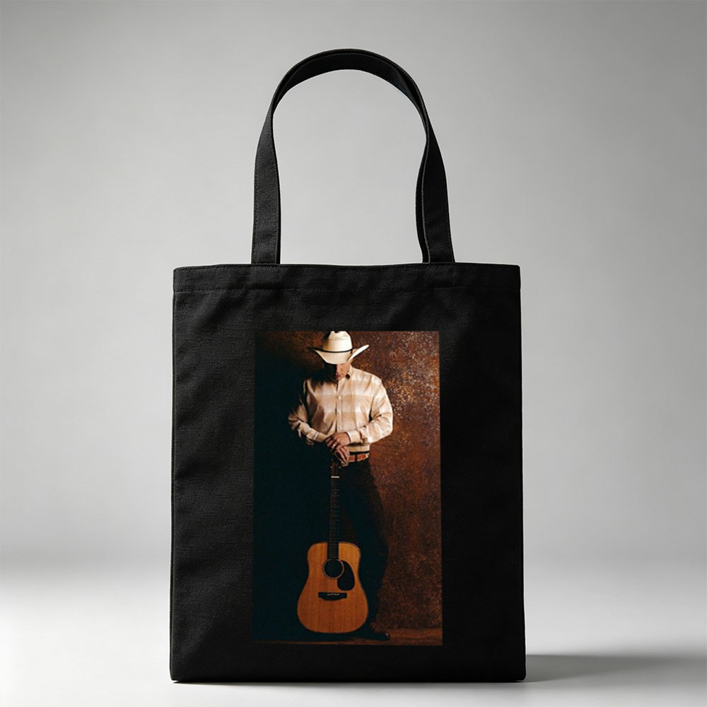 George Strait Holding Acoustic Guitar in Cowboy Attire Against Rustic Background - Canvas tote bags