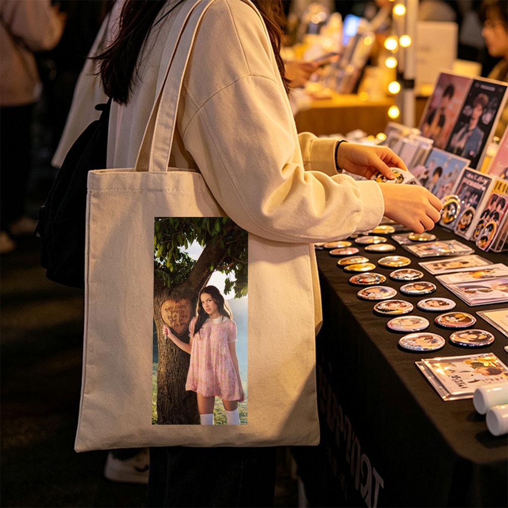 Olivia Rodrigo in a Romantic Outdoor Scene Wearing a Pink Floral Dress Leaning Against a Tree with a Heart Carved Message - Canvas tote bags