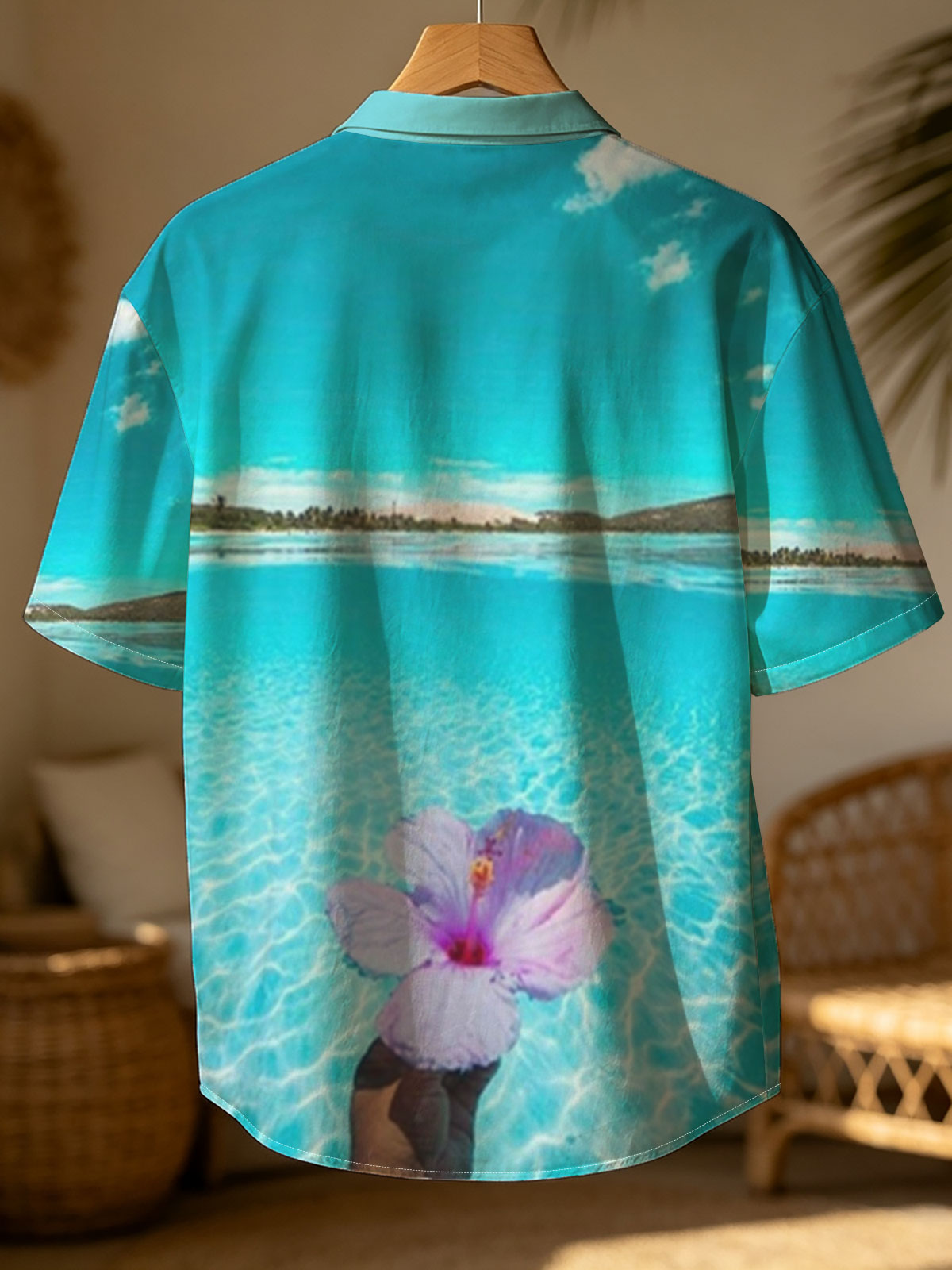 Hand holding a pink hibiscus flower over crystal-clear turquoise water under a bright blue sky. -  Shirt