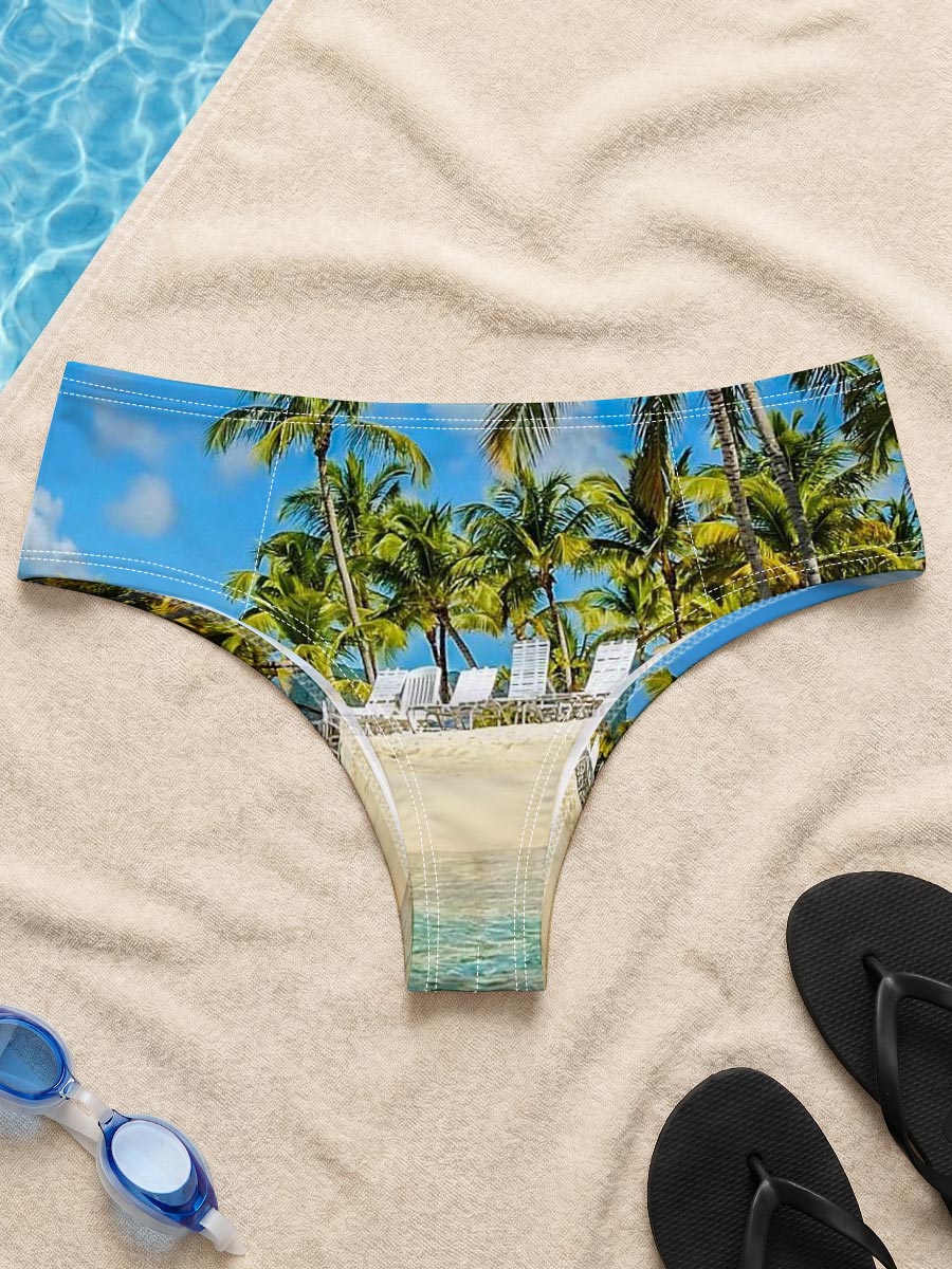 Crystal clear waters meet sandy beach with palm trees and lounge chairs under a bright blue sky. -  Men's swim trunks