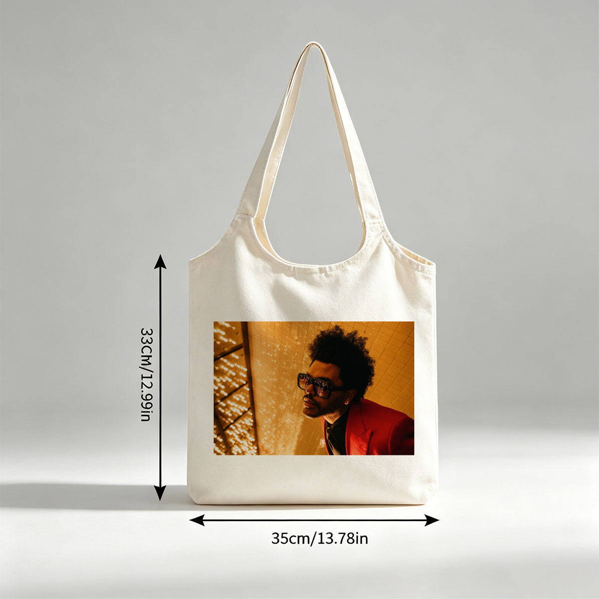 The Weeknd in a Red Suit and Sunglasses Against a Golden Lighted Background - Canvas shoulder bags/