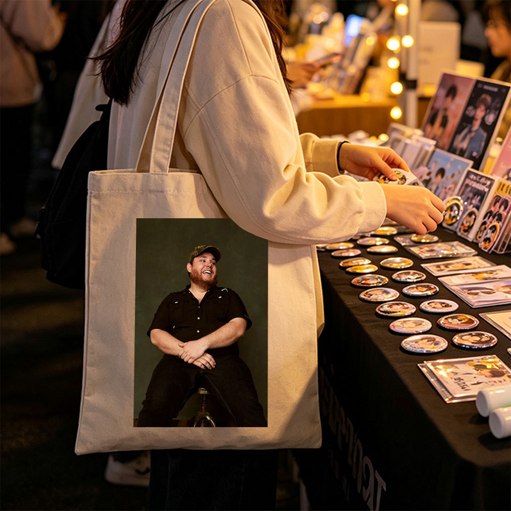 Luke Combs Sitting on a Stool Laughing in a Black Shirt and Cap - Canvas tote bags