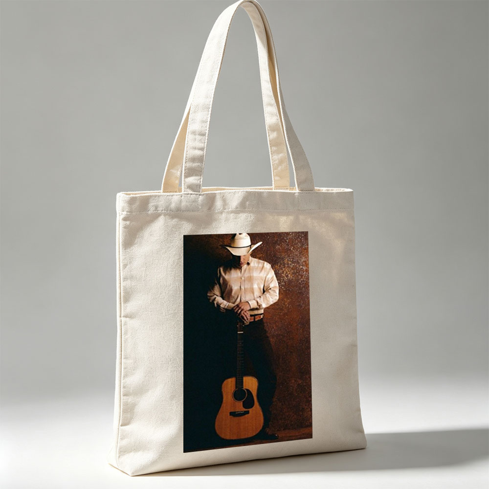 George Strait Holding Acoustic Guitar in Cowboy Attire Against Rustic Background - Canvas tote bags