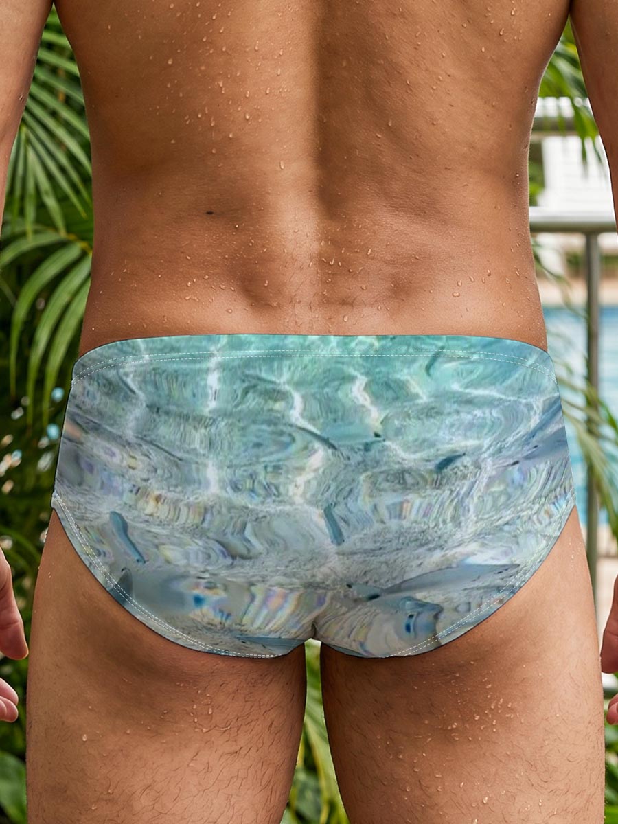 Clear waters reveal schools of fish swimming near a rocky shore with boats in the distance. -  Men's swim trunks
