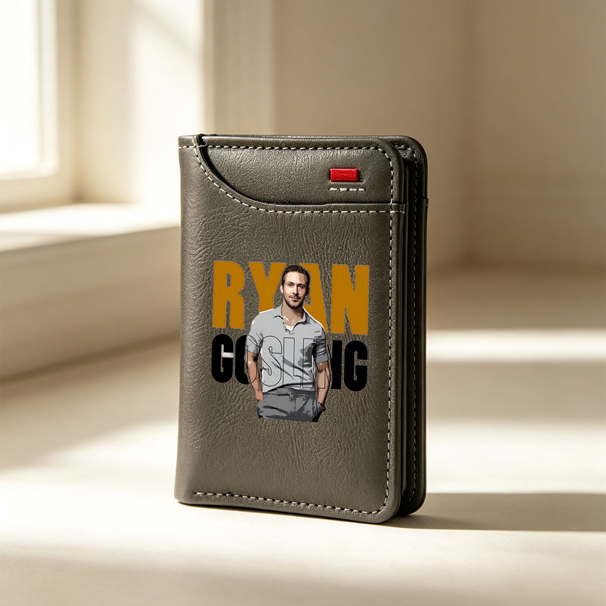 Ryan Gosling in a stylish gray polo shirt, standing confidently with hands in pockets, set against bold text backdrop. - Vertical Style Wallet
