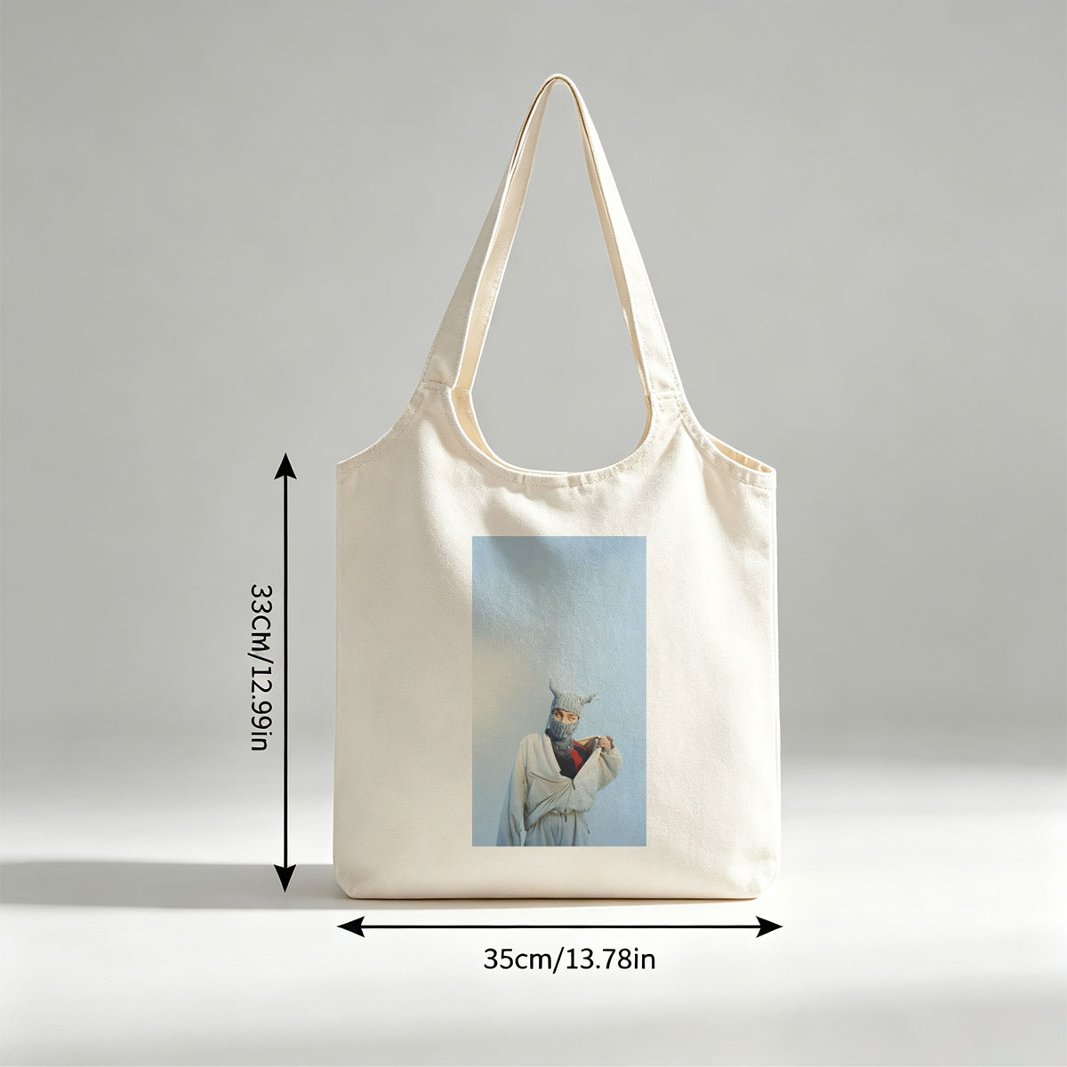 Billie Eilish in a whimsical winter scene wearing a horned knit mask and flowing white outfit against a clear blue sky - Canvas shoulder bags/