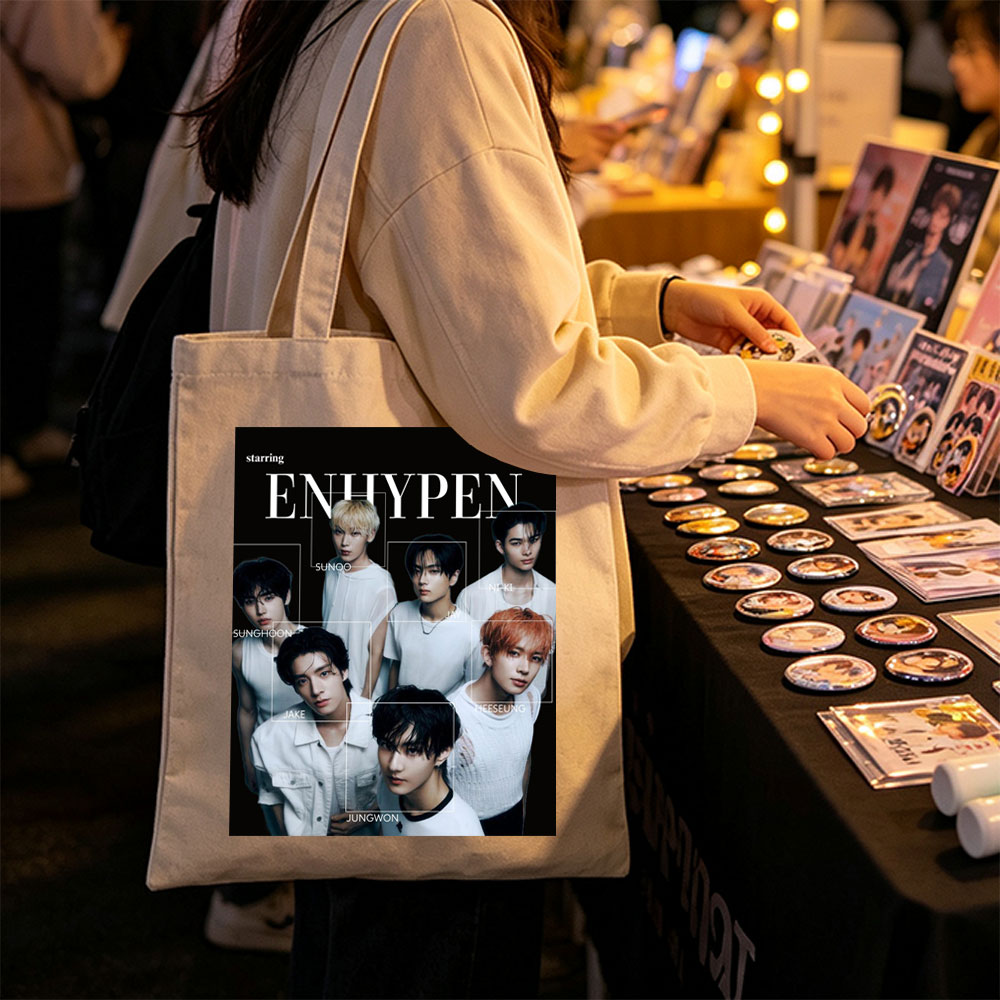 ENHYPEN in a striking black-and-white group portrait featuring all members in minimalist white outfits with individual name labels against a dark background - Canvas tote bags