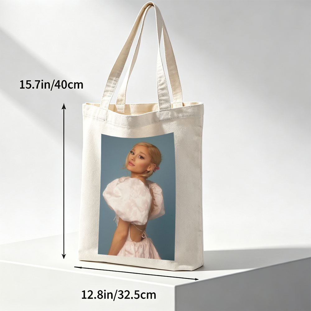 Ariana Grande in a Soft Pink Dress with Puffy Sleeves and Back Cutout Pose Against Blue Background - Canvas tote bags