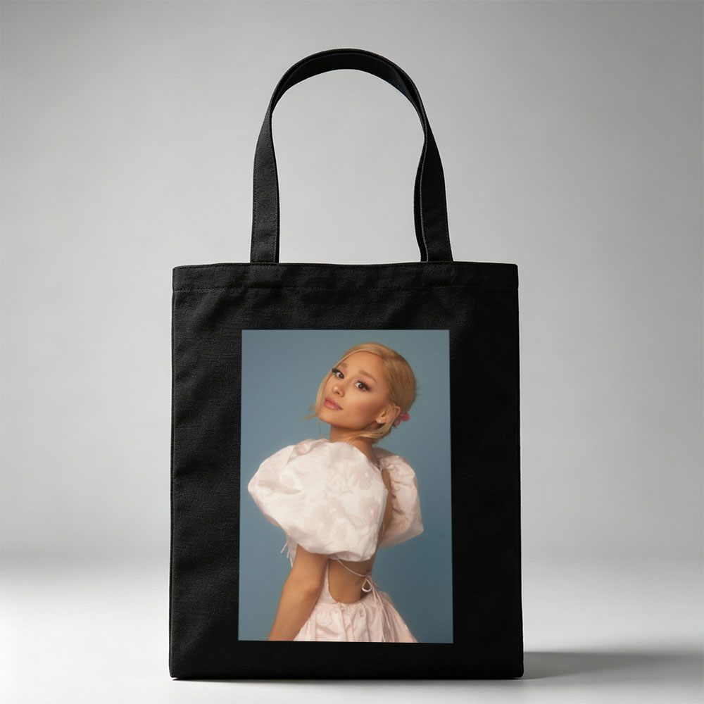 Ariana Grande in a Soft Pink Dress with Puffy Sleeves and Back Cutout Pose Against Blue Background - Canvas tote bags