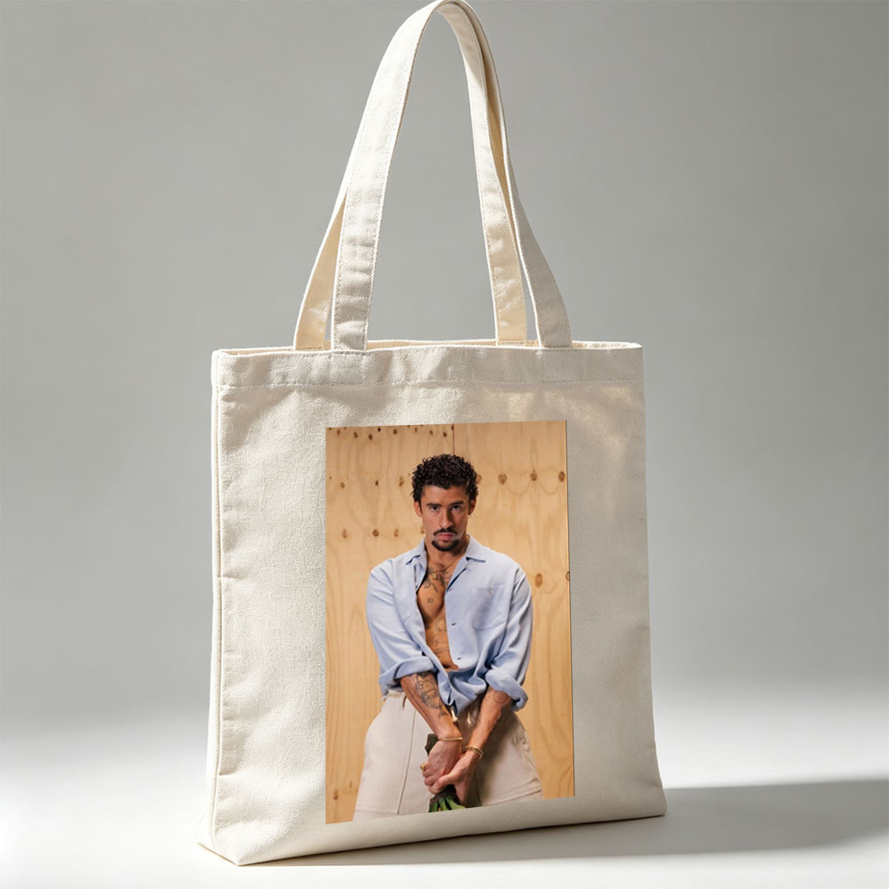 Bad Bunny in a Casual Pose Wearing an Open Light Blue Shirt and Beige Pants Against a Wooden Background - Canvas tote bags