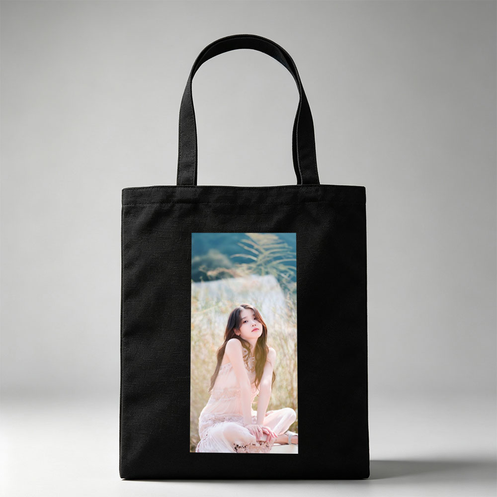 IU in a Serene Field Wearing a Delicate Pink Dress and Sitting Gracefully Amidst Tall Grass - Canvas tote bags