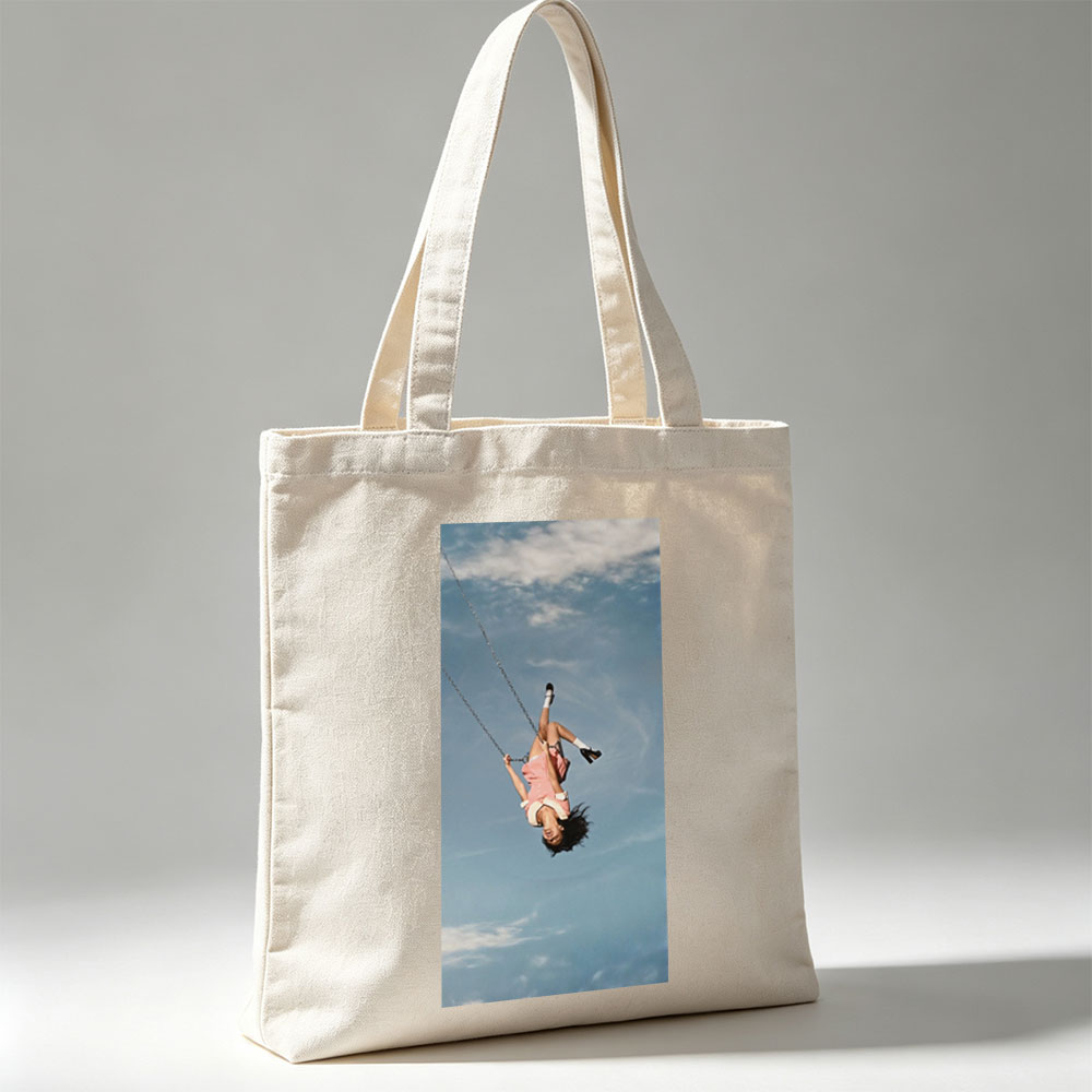 Taylor Swift Swinging on a Chain Against a Blue Sky - Canvas tote bags