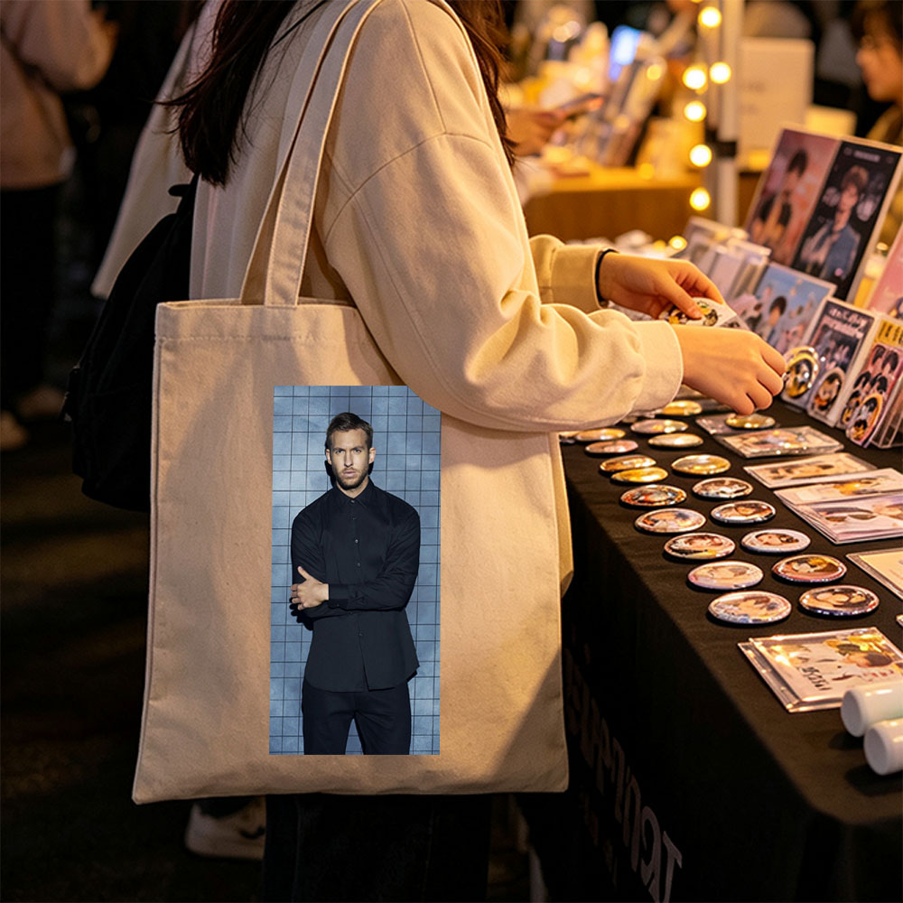 Calvin Harris in a Black Shirt and Pants Standing Against a Blue Tiled Wall with Arms Crossed - Canvas tote bags