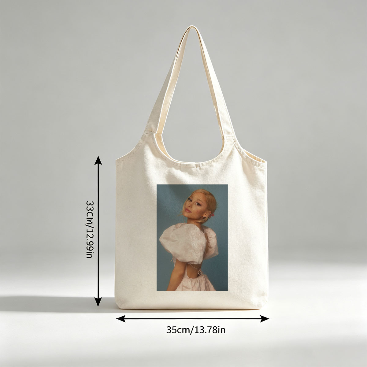 Ariana Grande in a Soft Pink Dress with Puffy Sleeves and Back Cutout Pose Against Blue Background - Canvas shoulder bags/