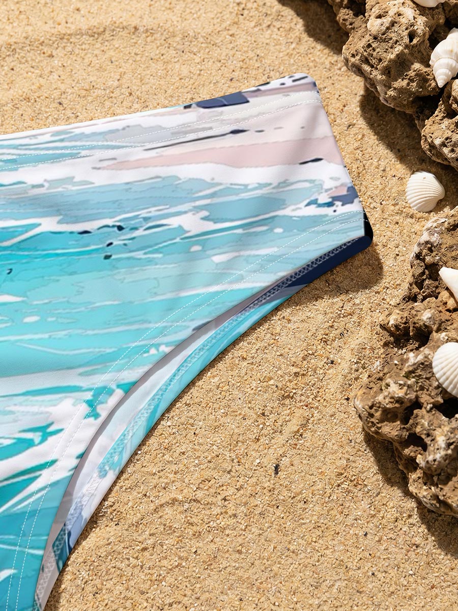 Turquoise waves crash on a rocky beach with distant city skyline and lush green hills under a bright sky. -  Men's swim trunks