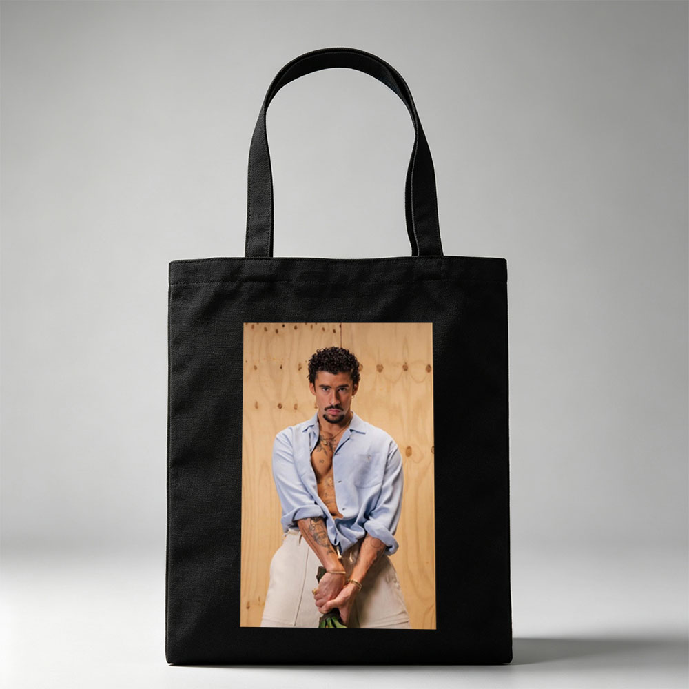 Bad Bunny in a Casual Pose Wearing an Open Light Blue Shirt and Beige Pants Against a Wooden Background - Canvas tote bags