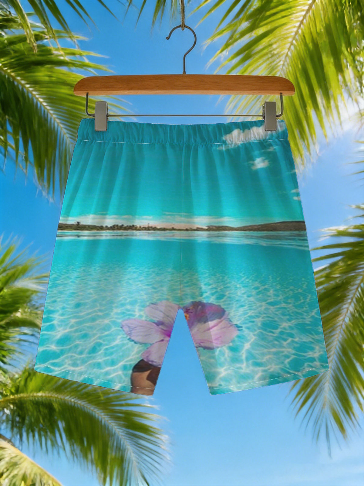 Hand holding a pink hibiscus flower over crystal-clear turquoise water under a bright blue sky. -  Beach shorts