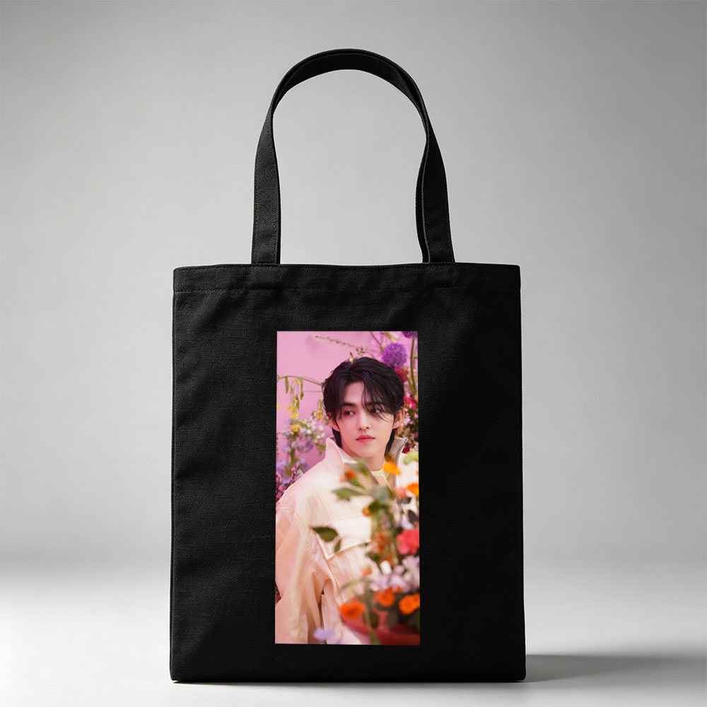Sungchan in a floral garden, wearing a soft pink jacket with vibrant flowers in the foreground - Canvas tote bags