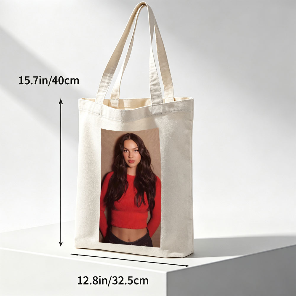 Olivia Rodrigo in a Bold Red Crop Top and Jeans, Striking a Confident Pose Against a Textured Background - Canvas tote bags