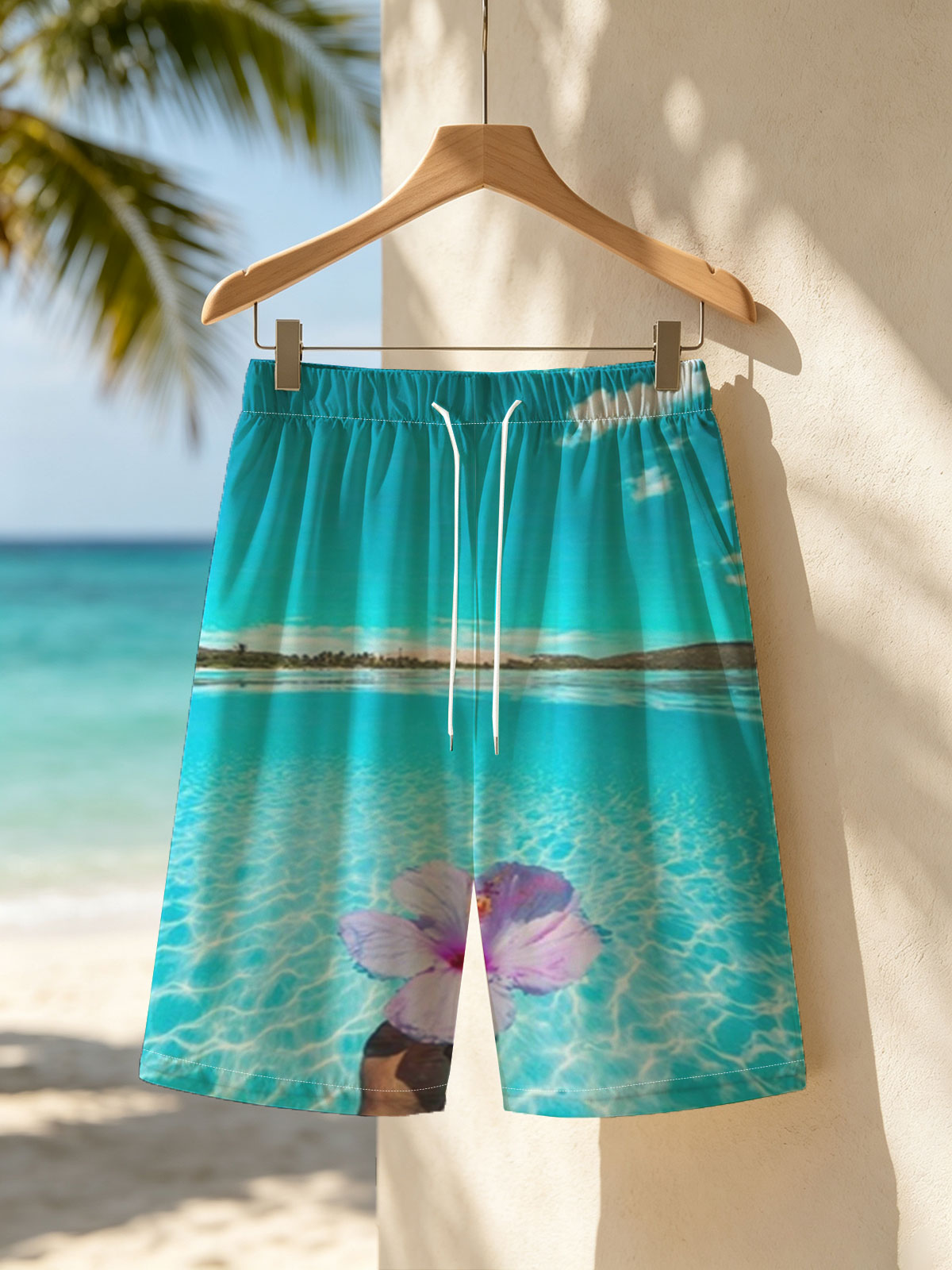 Hand holding a pink hibiscus flower over crystal-clear turquoise water under a bright blue sky. -  Beach shorts