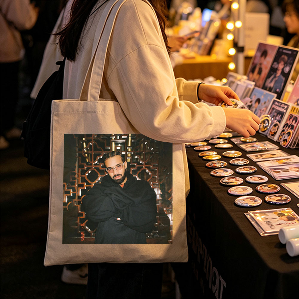 Drake in a Stylish Pose Against an Ornate Background Wearing Glasses and a Black Hoodie - Canvas tote bags
