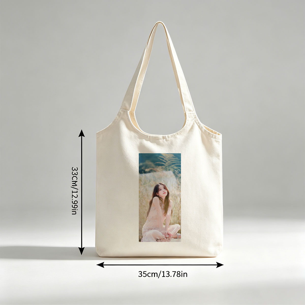 IU in a Serene Field Wearing a Delicate Pink Dress and Sitting Gracefully Amidst Tall Grass - Canvas shoulder bags/