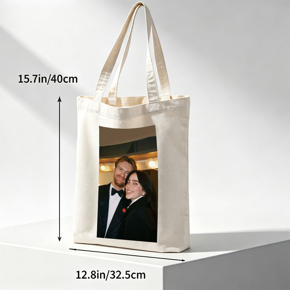 Lily Collins and Sam Claflin at a glamorous event, smiling together in formal attire with warm lighting in the background. - Canvas tote bags