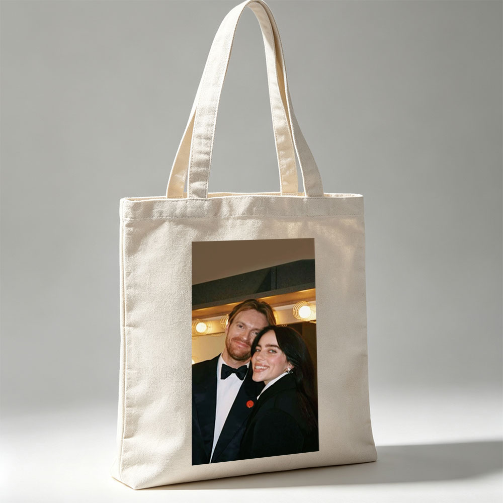 Lily Collins and Sam Claflin at a glamorous event, smiling together in formal attire with warm lighting in the background. - Canvas tote bags