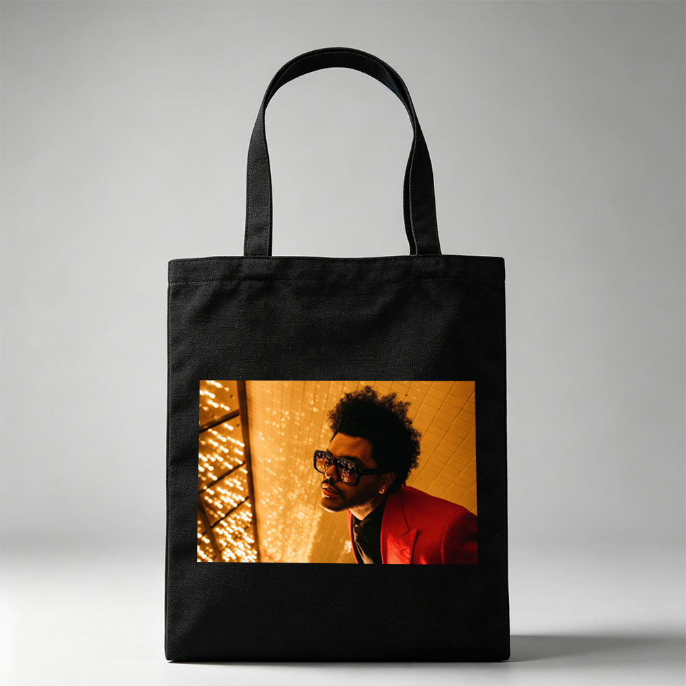 The Weeknd in a Red Suit and Sunglasses Against a Golden Lighted Background - Canvas tote bags