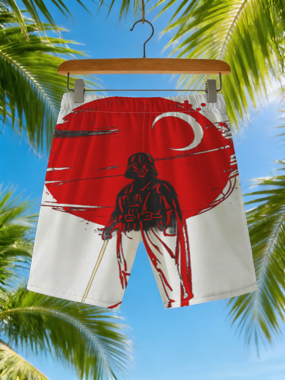 Darth Vader stands before a red sun, wielding a lightsaber in a dramatic silhouette. -  Beach shorts