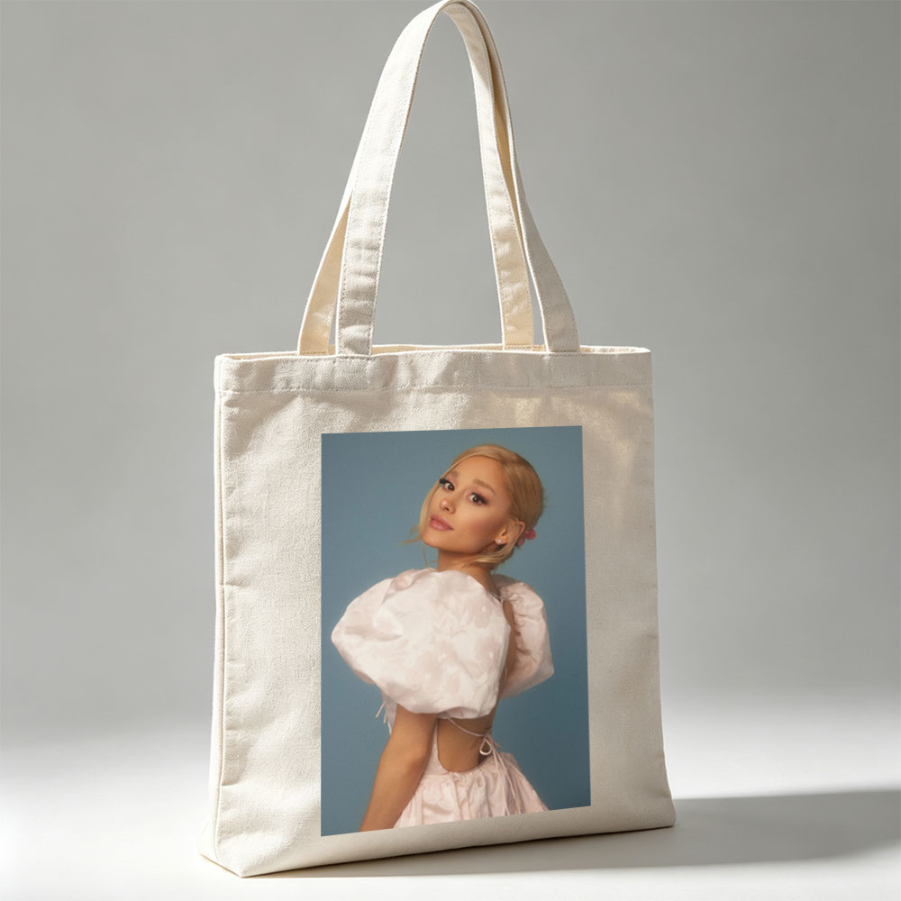 Ariana Grande in a Soft Pink Dress with Puffy Sleeves and Back Cutout Pose Against Blue Background - Canvas tote bags