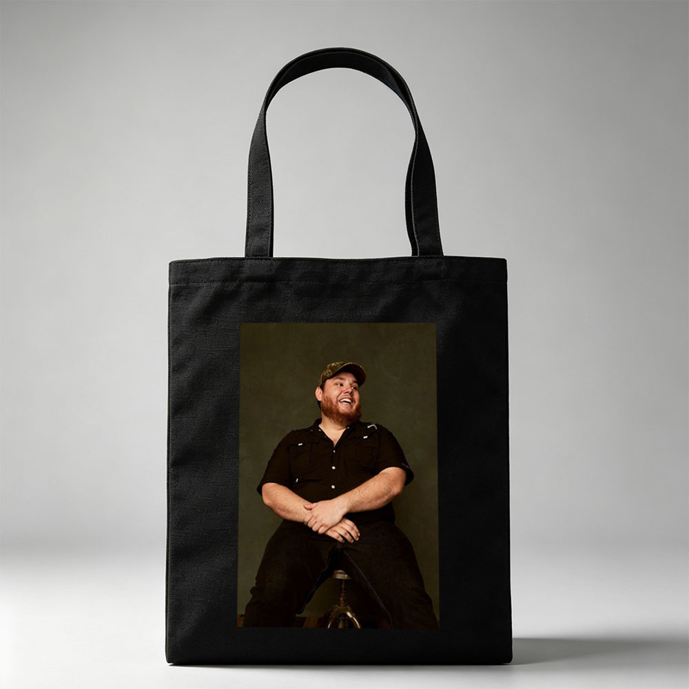 Luke Combs Sitting on a Stool Laughing in a Black Shirt and Cap - Canvas tote bags