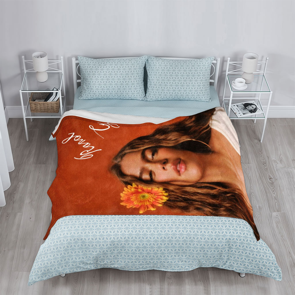 Ranal G with a vibrant orange flower in her hair against a warm terracotta background - Blankets
