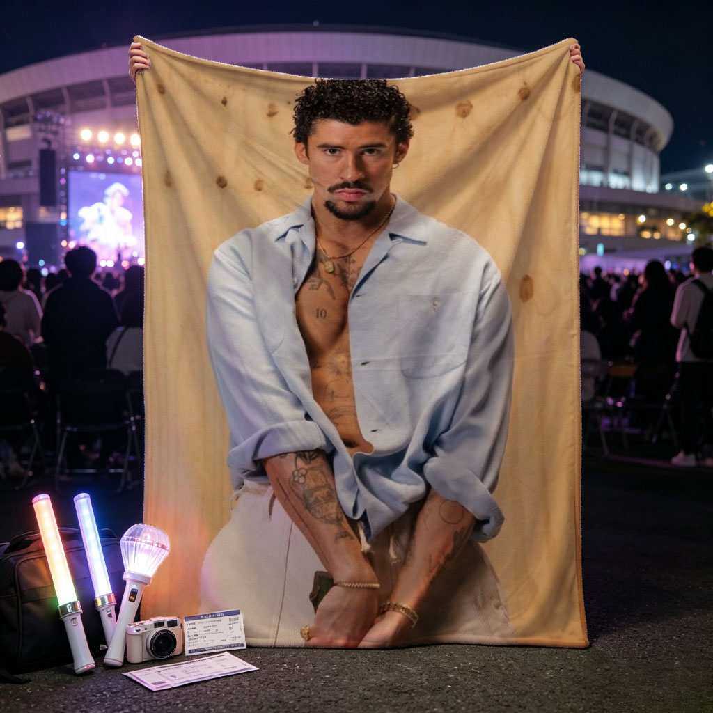 Bad Bunny in a Casual Pose Wearing an Open Light Blue Shirt and Beige Pants Against a Wooden Background - Blankets