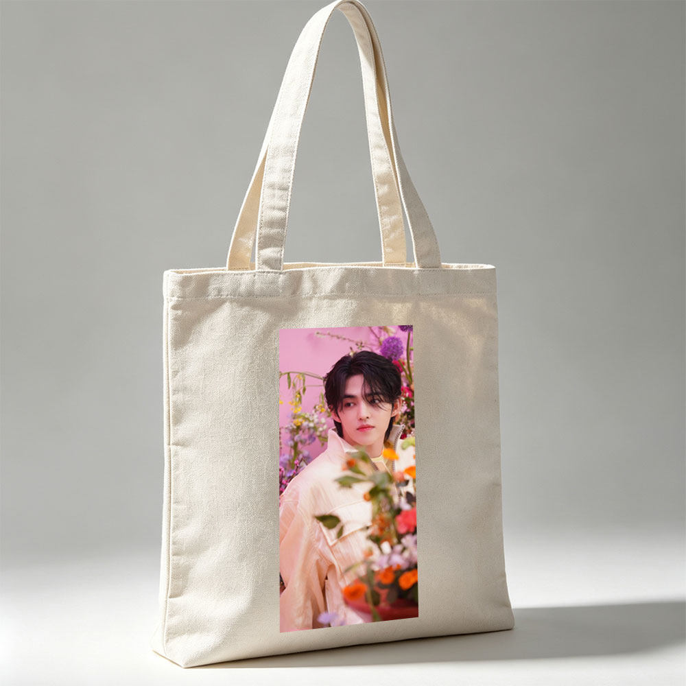 Sungchan in a floral garden, wearing a soft pink jacket with vibrant flowers in the foreground - Canvas tote bags