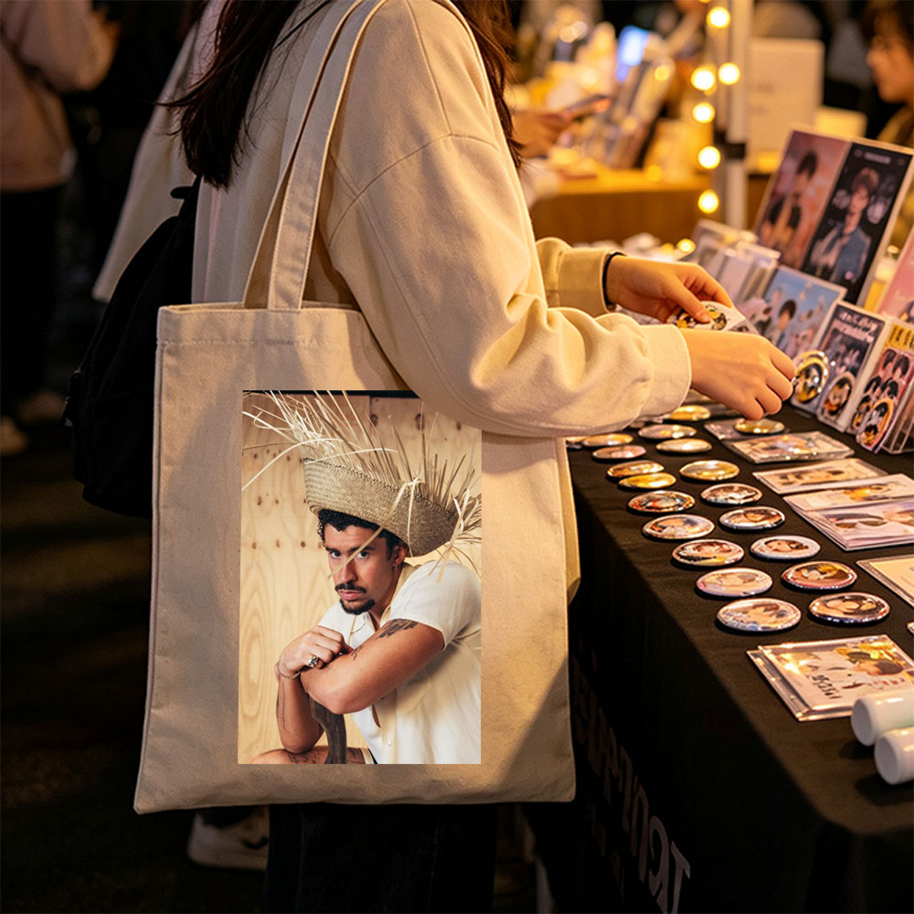 Bad Bunny Wearing a Straw Hat with Hay Sticks, Leaning Against a Wooden Wall in a Casual Pose - Canvas tote bags