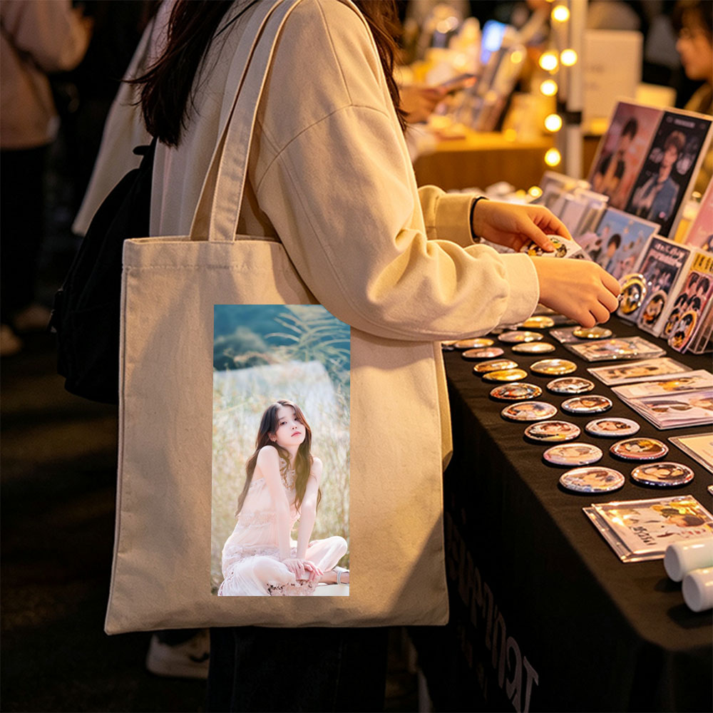 IU in a Serene Field Wearing a Delicate Pink Dress and Sitting Gracefully Amidst Tall Grass - Canvas tote bags