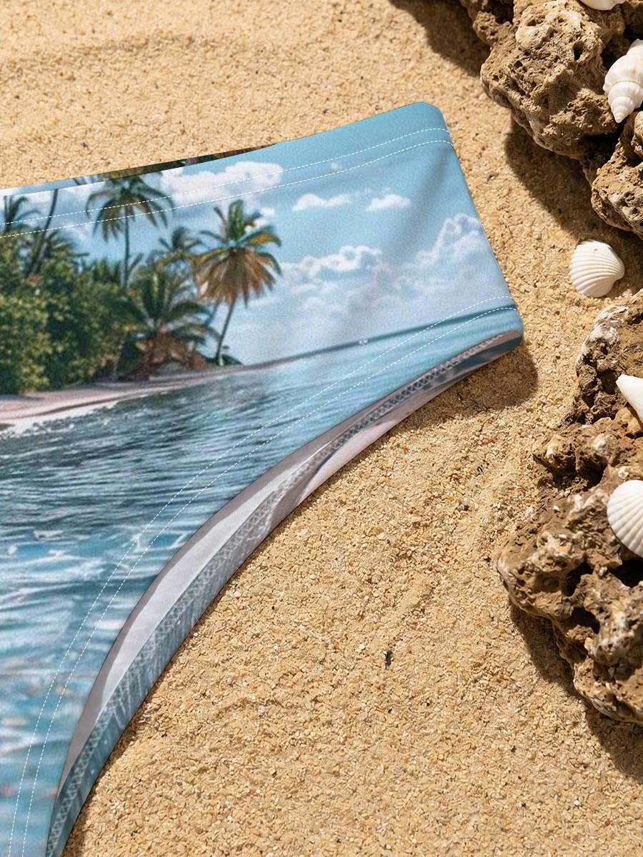 Crystal-clear waters lap against a serene tropical beach lined with swaying palm trees under a bright blue sky. -  Men's swim trunks