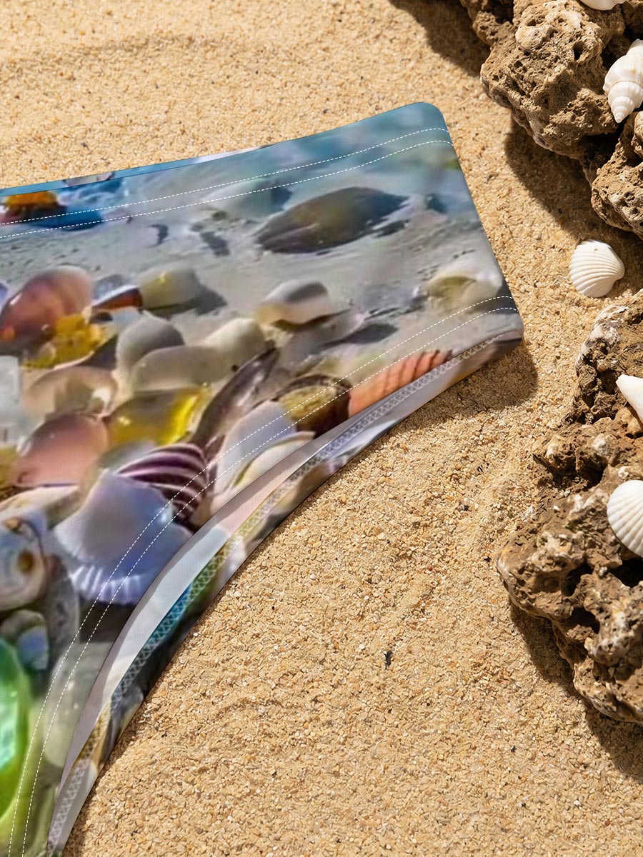 Colorful seashells on a tropical beach with clear blue water and sky. -  Men's swim trunks