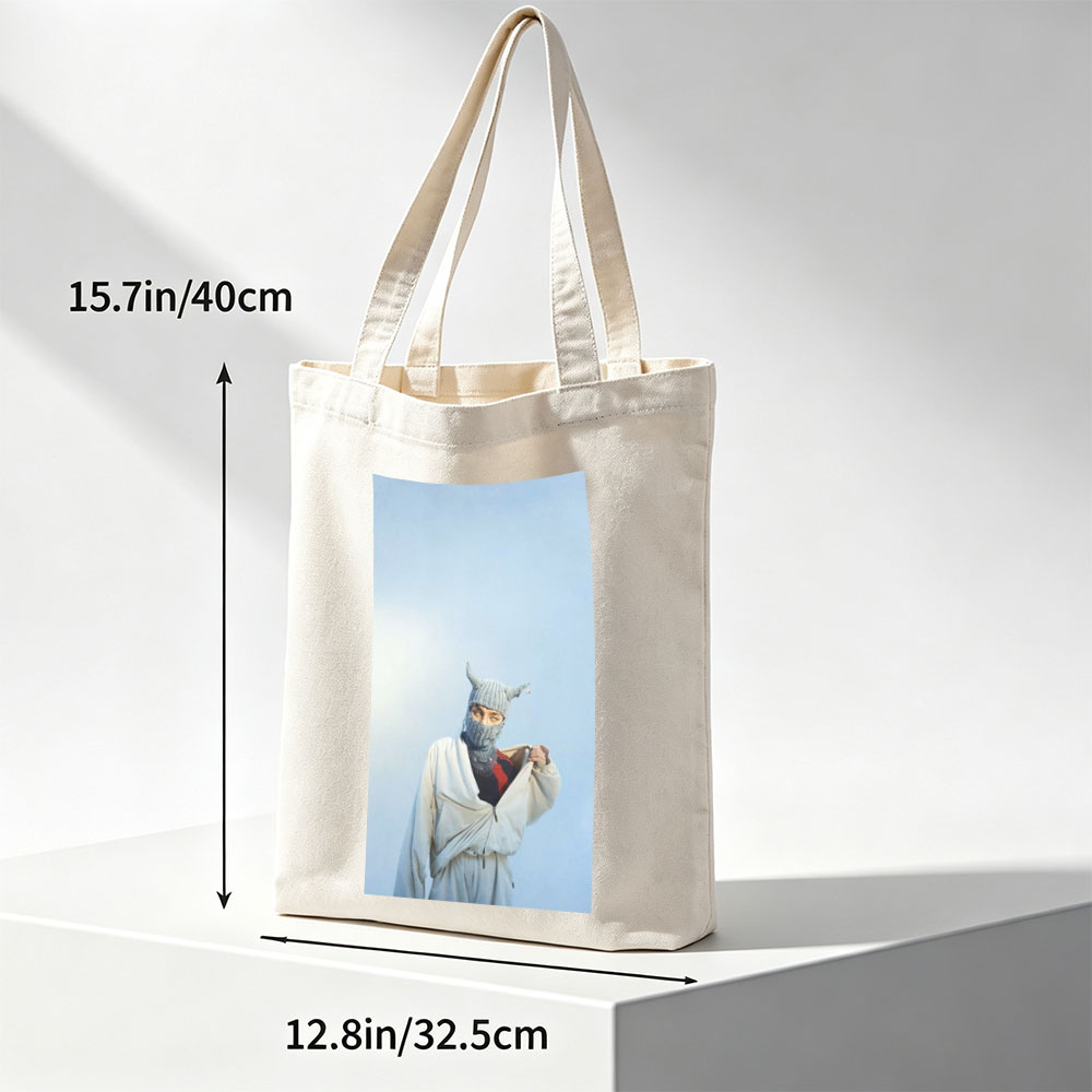 Billie Eilish in a whimsical winter scene wearing a horned knit mask and flowing white outfit against a clear blue sky - Canvas tote bags