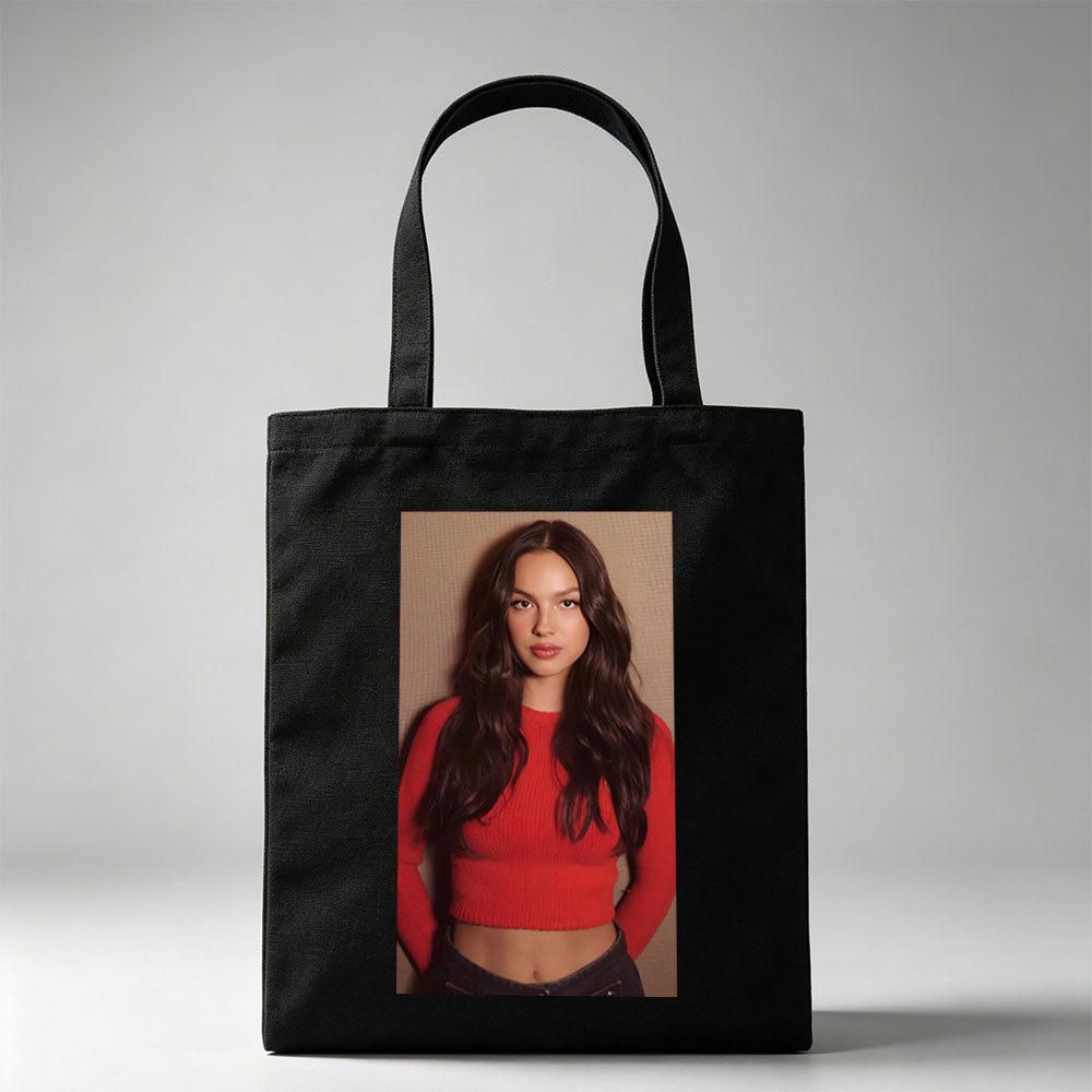Olivia Rodrigo in a Bold Red Crop Top and Jeans, Striking a Confident Pose Against a Textured Background - Canvas tote bags
