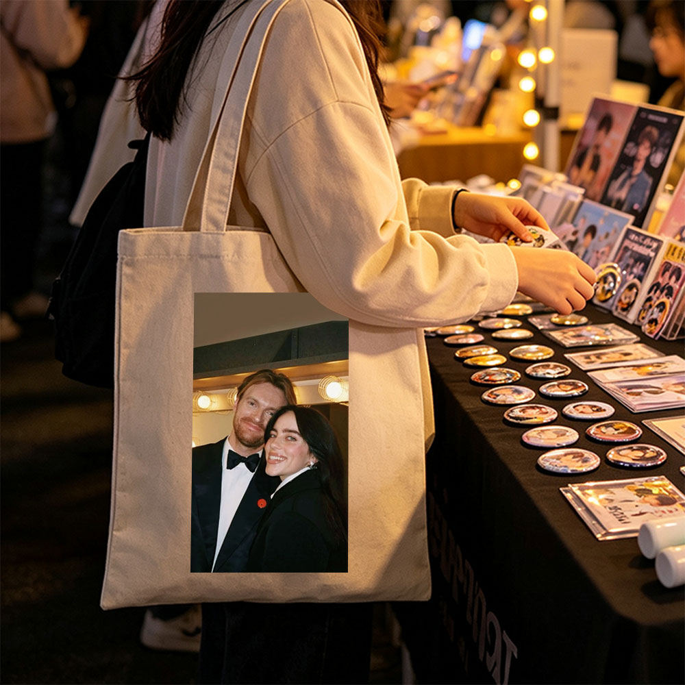 Lily Collins and Sam Claflin at a glamorous event, smiling together in formal attire with warm lighting in the background. - Canvas tote bags