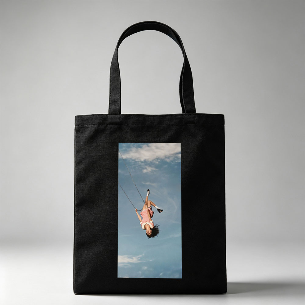 Taylor Swift Swinging on a Chain Against a Blue Sky - Canvas tote bags