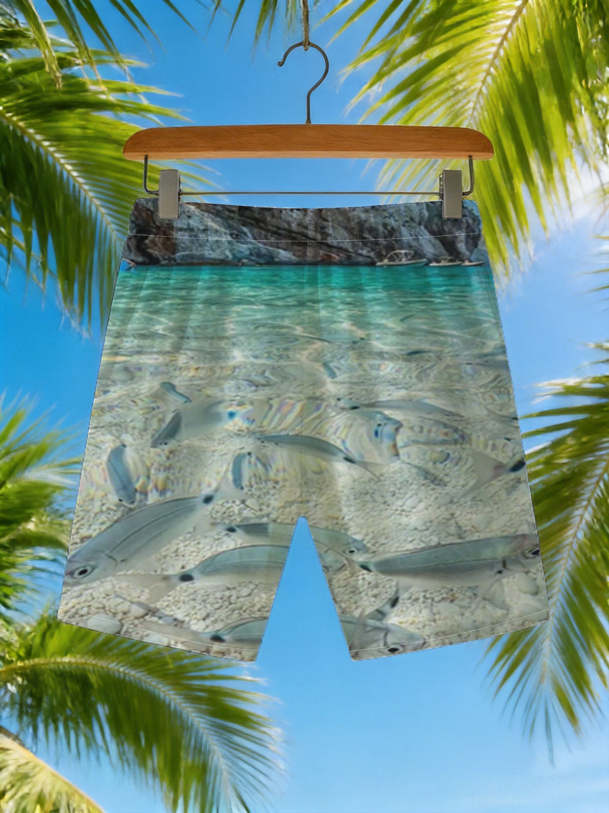 Clear waters reveal schools of fish swimming near a rocky shore with boats in the distance. -  Beach shorts