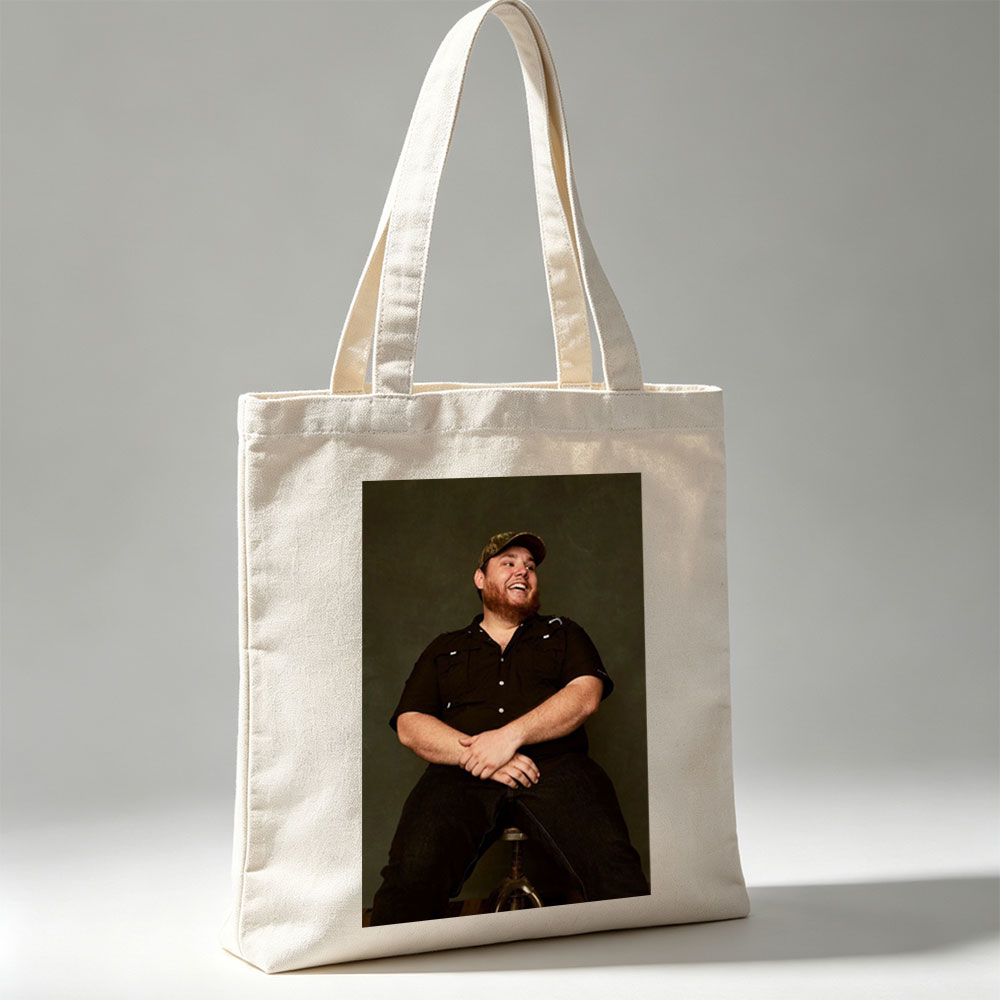 Luke Combs Sitting on a Stool Laughing in a Black Shirt and Cap - Canvas tote bags