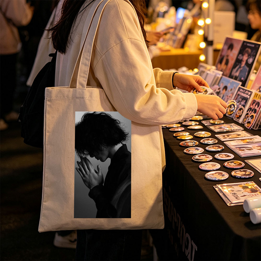 Yojiro Noda in a contemplative pose with hands clasped, captured in dramatic black and white lighting. - Canvas tote bags