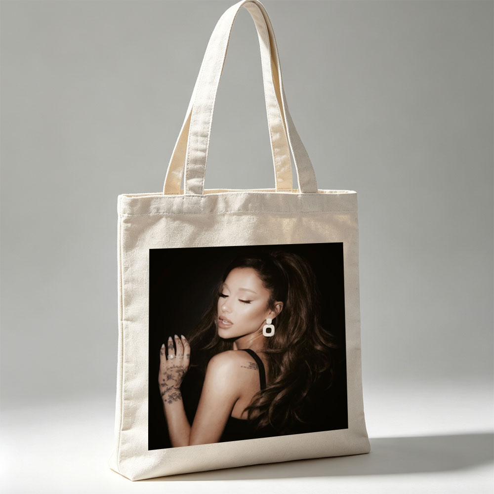 Ariana Grande in a Dramatic Pose with Long Hair and Tattoos on Dark Background - Canvas tote bags