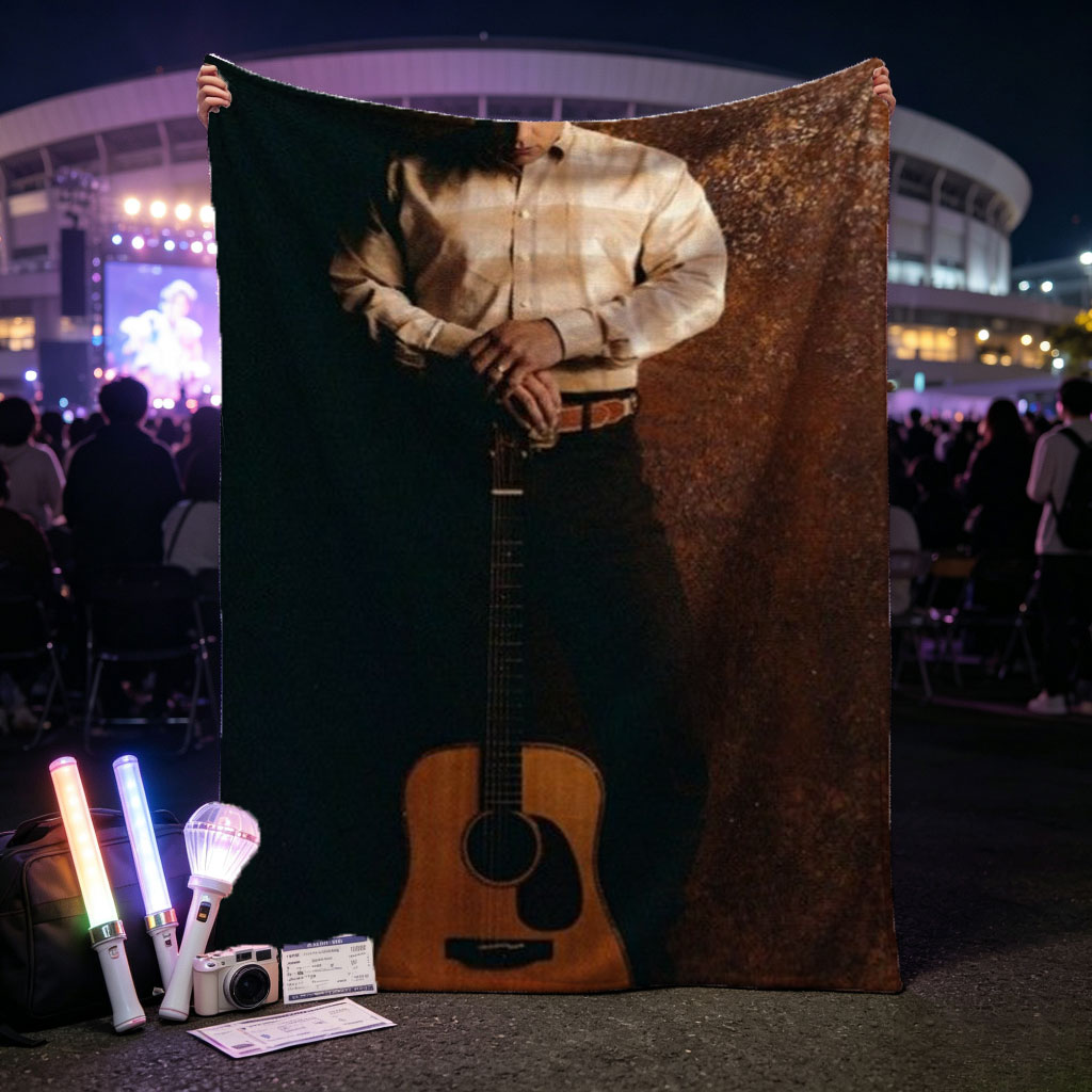 George Strait Holding Acoustic Guitar in Cowboy Attire Against Rustic Background - Blankets