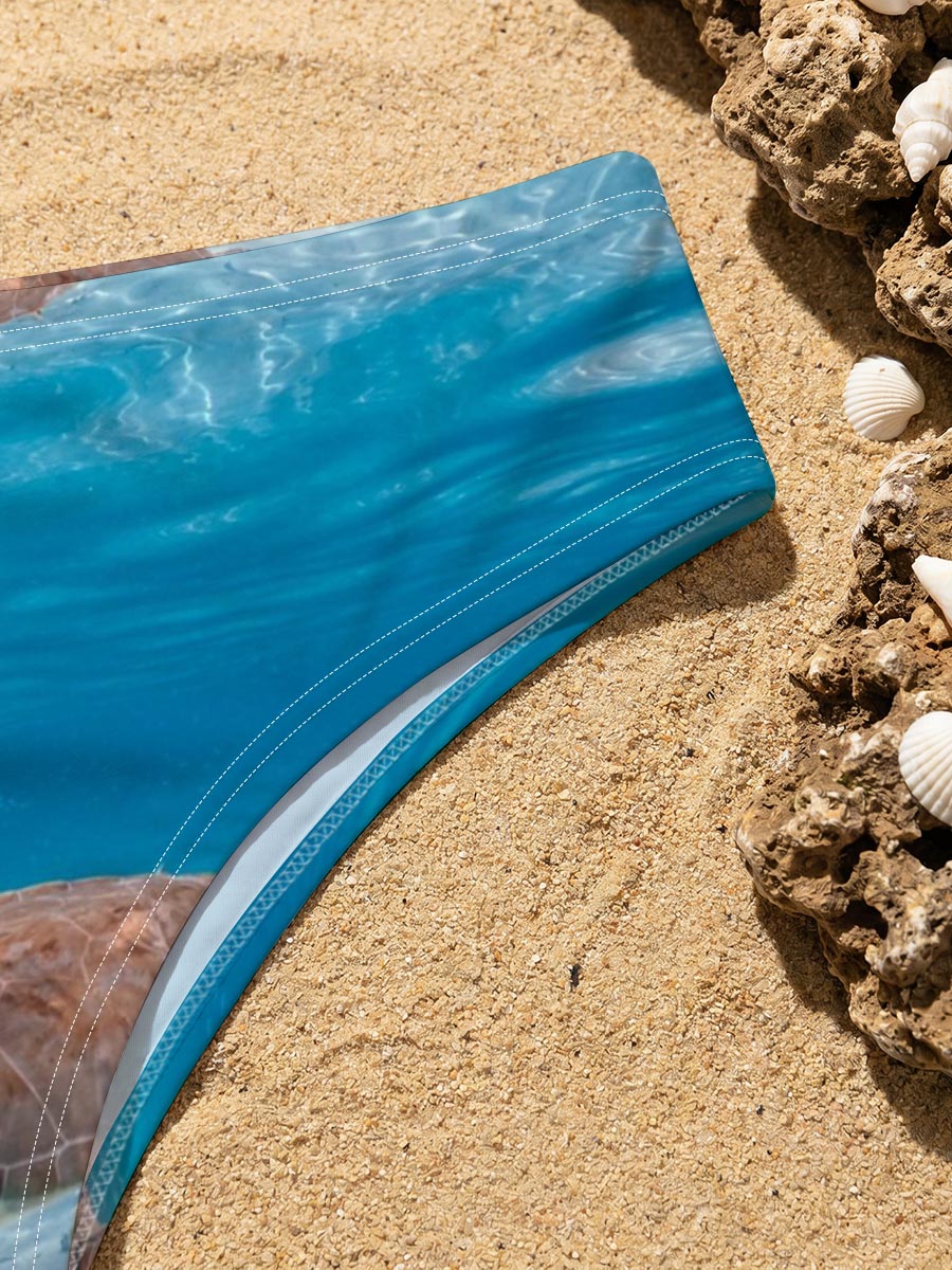 Sea turtle swims gracefully in clear blue water with fish below, sunlight filtering through the surface. -  Men's swim trunks