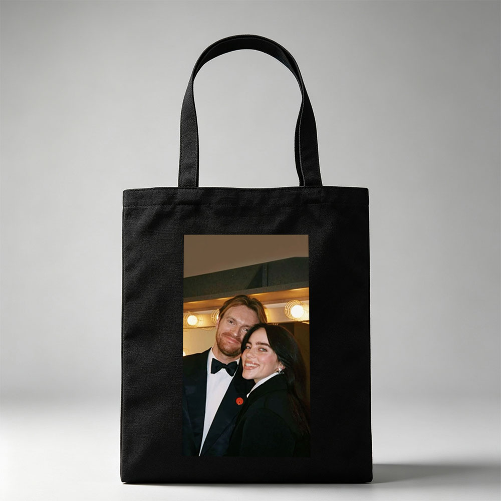 Lily Collins and Sam Claflin at a glamorous event, smiling together in formal attire with warm lighting in the background. - Canvas tote bags